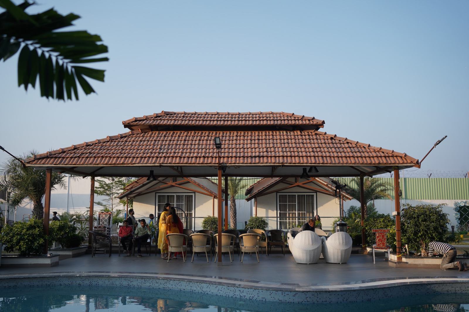 Tiled-roof gazebo by the pool with cottages behind