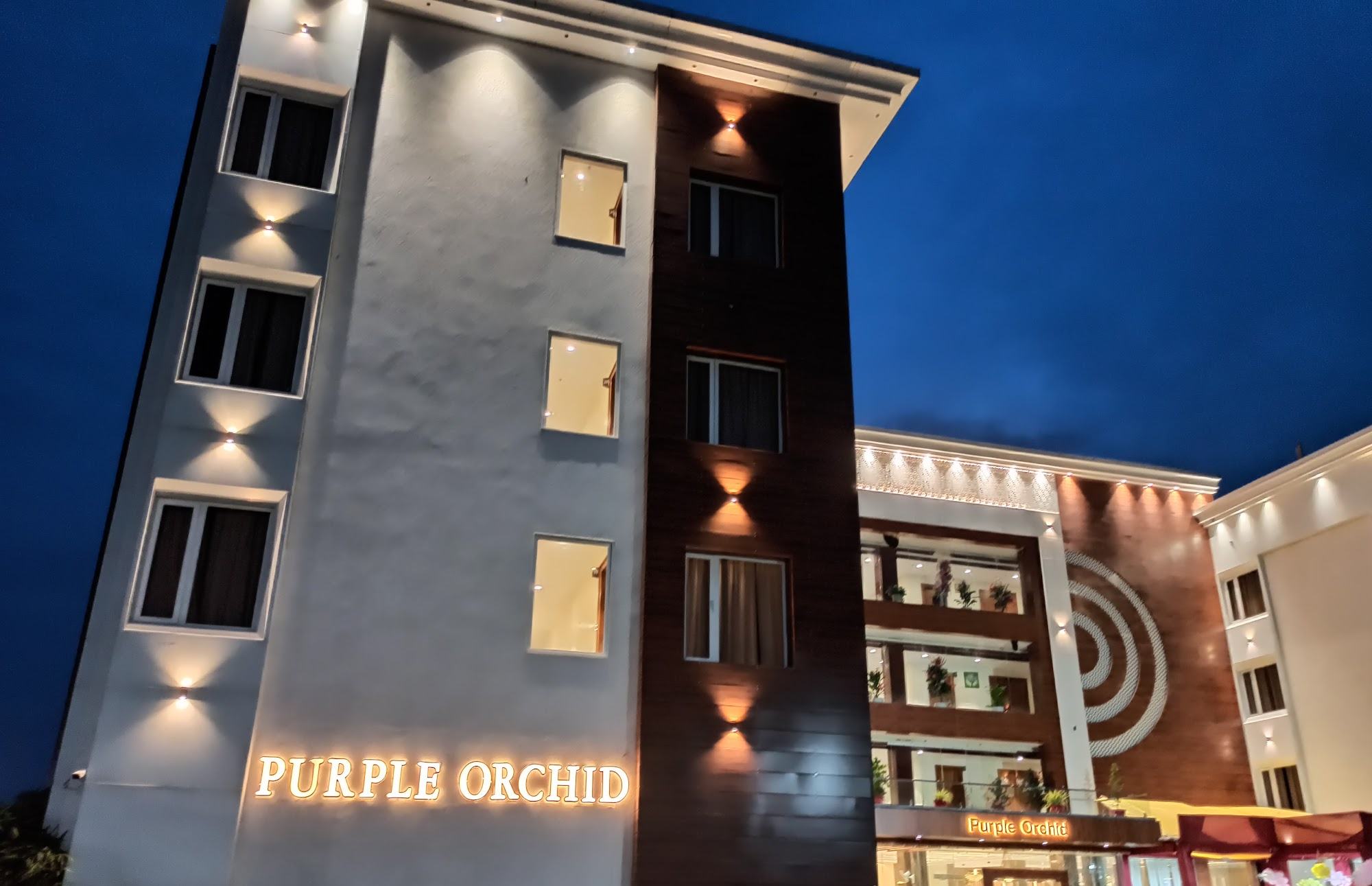 The main building lit up at dusk with the Purple Orchid sign